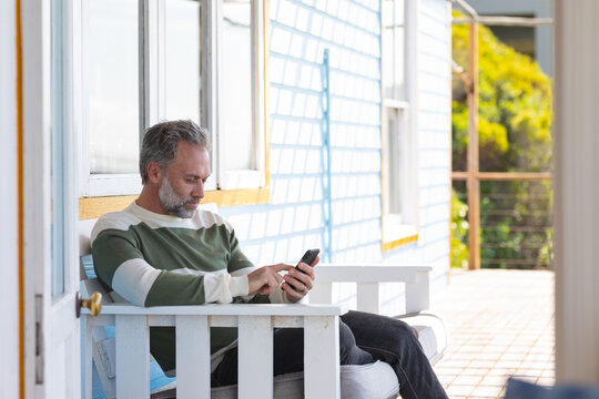 Caucasian mature man using smartphone on a terrace by the sea