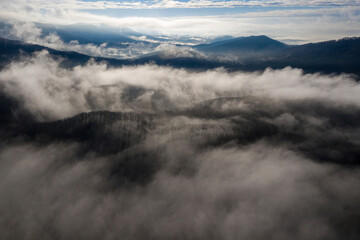 Back lighting aerial view of covered with clouds mountains close to Gelendzhik on sunny winter...