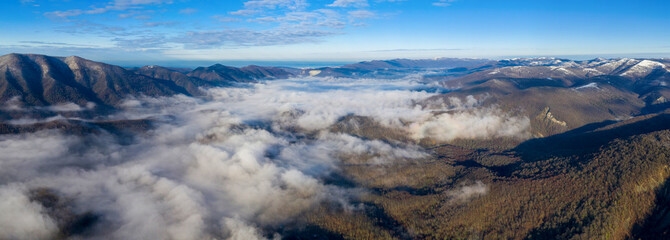 Panoramic aerial view of covered with fog mountain valley close to Gelendzhik on sunny winter day. Krasnodar Krai, Russia.