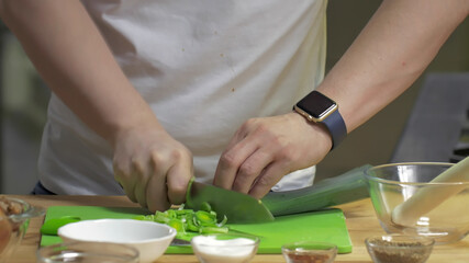 Obraz na płótnie Canvas Cropped shot of chef slicing green leek in professional kitchen