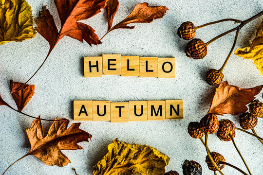 Autumnal hello autumn message with dried autumn leaves and berries on a table