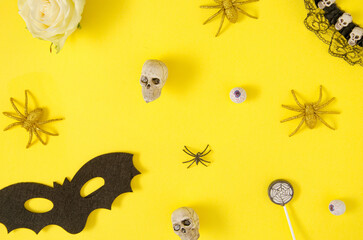 Colorful Halloween concept with skulls, spiders, bats, and eyeballs on vivid yellow background. Creative celebration idea.