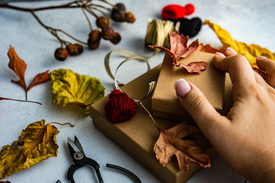 Woman's hand decorating autumnal gift boxes
