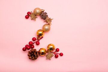 number 2 made with Christmas ornaments on a pink background