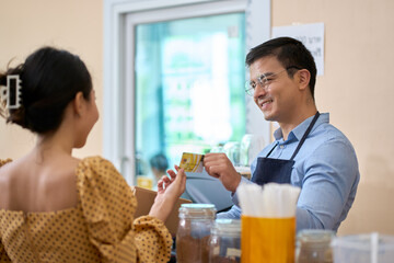 Owner of coffee shop receive credit card from customer for paid item in shop