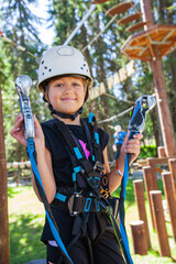 Portrait of smiling little girl in safety equipment at adventure park