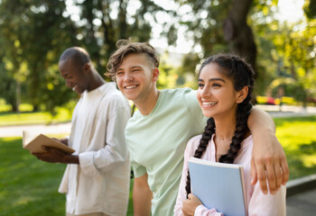 Free time of students. Happy diverse university friends walking together in campus, chatting and laughing outdoors