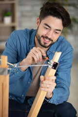 young man assembling wooden furniture at home