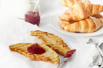 Grilled croissants with strawberry jam on white tablecloth. breakfast.