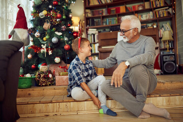 Happy grandfather and grandson talk while spending Christmas together at home.