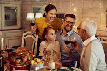 Cheerfully extended family toasts with celebrating Thanksgiving at dining table.