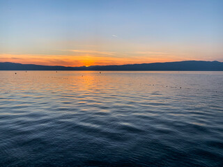 Beautiful sunset on the lake, natural colors, silhouette of the mountains background, deep blue color