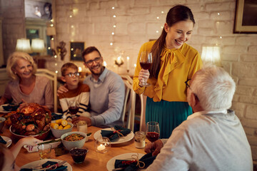 Happy woman holds a toast during Thanksgiving dinner with her family at home.