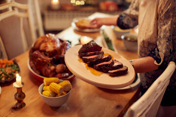 Close-up of woman serves food at dining table on Thanksgiving,
