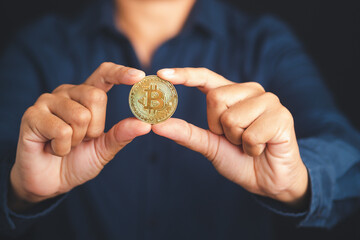 Investor holding a bitcoin coin in his hand. Bitcoin is a symbol of cryptocurrency, electronic virtual money. Close-up photo. Blockchain technology, payment, and digital asset concept
