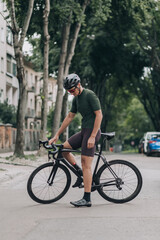 Fototapeta na wymiar Sporty man standing with bike on empty city street