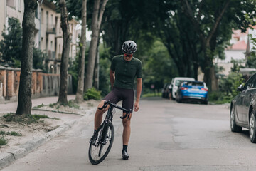 Fototapeta na wymiar Sporty man standing with bike among empty city street