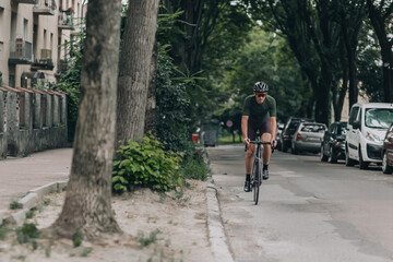 Muscular man in sportswear cycling along city street
