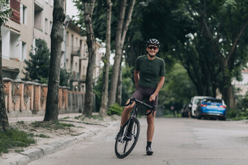 Fototapeta na wymiar Positive cyclist with bike resting on street after ride