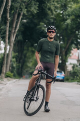 Fototapeta premium Muscular man in sport clothes sitting on bike on city street