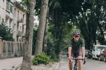 Fototapeta premium Smiling man riding bike in safety helmet along city street