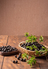 Jabuticaba, Jabuticabas freshly harvested and not yet washed, placed in a straw basket and wooden bowl on rustic wood, selective focus.