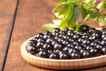 Jabuticaba, Jabuticabas freshly harvested in pots and baskets arranged on rustic wood, selective focus.