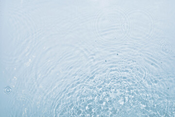 Fototapeta na wymiar Blue water background with round streaks of drops dripping and creating vibrations, top view