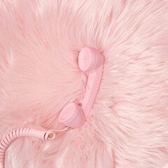 Pastel pink retro telephone handset and pastel pink faux fur background. Vintage aesthetic 80s or 90s fashion background. Romantic communication idea.