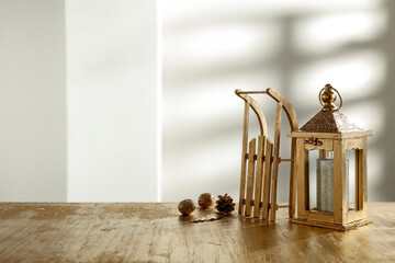 Wooden table with blank and golden Christmas accessories on the background of the wall with a shadow 
