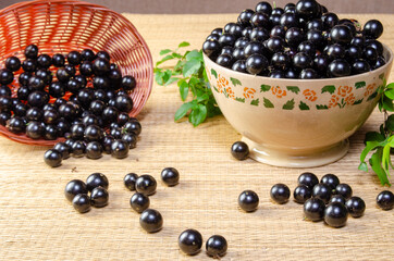 Jabuticaba, Jabuticabas freshly harvested in a bowl and baskets arranged on a straw mat, selective focus.