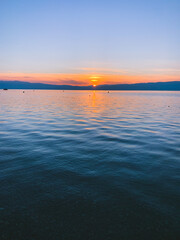 Beautiful sunset on the lake, natural colors, silhouette of the mountains background, deep blue color