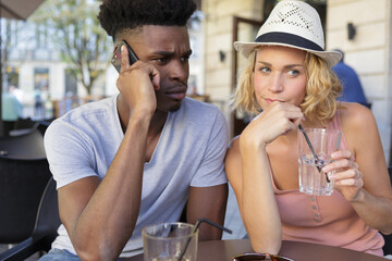 man on the phone while girlfriend is drinking juice