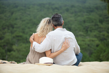 Fototapeta premium senior couple hugging looking at forest from dunes on beach