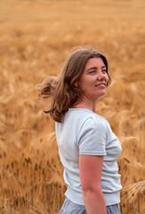 happy girl is having fun with her hair spread out in wheat field. Healthy young woman outdoors. Walking through field of rye