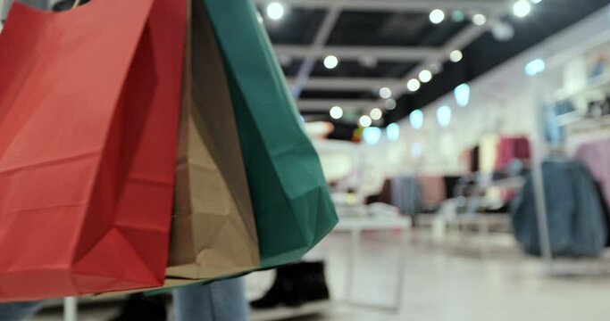 Close up of young woman walks with colorful shopping bags around a shopping mall. Shopping after quarantine.