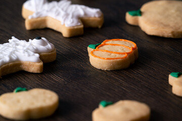 Decorating cute Halloween pumpkin cookies with frosting in icing bag.