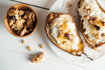 top view of sweet pears stuffed with cream cheese and nuts. grilled fruits as vegetarian dessert. white rustic table. honey topping for autumn treat.