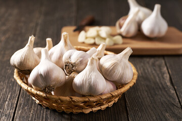 whole garlic bulbs in a basket on a wooden table.
