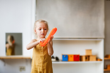 Cute Caucasian Girl Child Wearing Muslin Jumpsuit Plays With Two Pop Tubes, Fashion Fidget Finger Toys, Mini Tubes Stretch Pull Tube