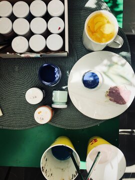 Cup of ginger and turmeric tea on a table with pots of paint and painting equipment