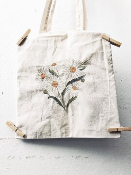 Freshly painted tote bag with a daisy flower pattern drying