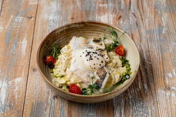 A portion of fish and potato gratin with rich creamy sauce with a poached egg, close very appetizing view