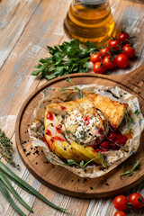 Golden baked brie with apple, cranberry sauce and herbs on rustic wooden tray, top view for a menu