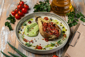 Baked and stuffed with vegetables half of eggplant on a beautiful plate, rustic-style serving, beautiful menu commercial photography