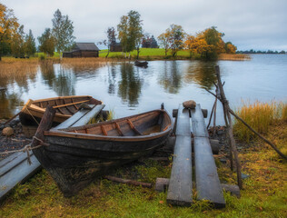 A village fishing boat made of boards in the Kizhi Museum Reserve in the north of Russia on Lake Onega with docks and a pier in golden autumn time..