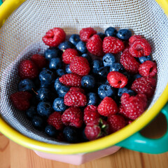Delicious juicy ripe wild berries raspberries and blueberries in colorant. Washed berries for breakfast