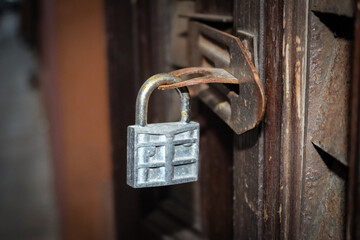 Iron padlock hanging on wooden brown door