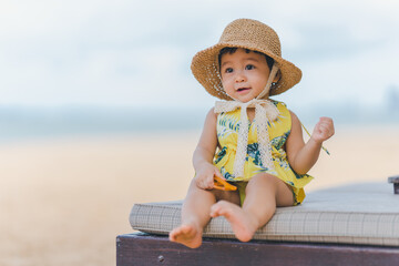 A baby with moments of excitement and joy to be out at sea. by sitting on a beach chair and wearing...