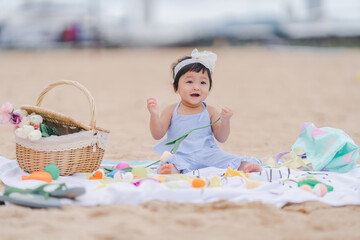 A cute baby is happy on a bright and early morning day on the beach while enjoying the concept picnic with fun emotions and learning along the way.